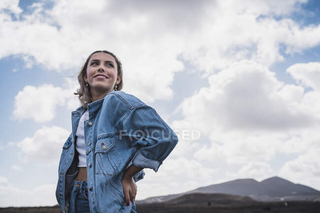 Смолящий в сторону, стоя на фоне неба на вулкане Эль-Куэрво, Лароте, Испания — стоковое фото