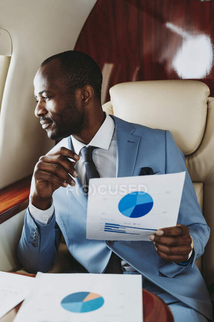 Бізнесмен з діаграмою пирога, який дивиться через вікно в літаку — стокове фото