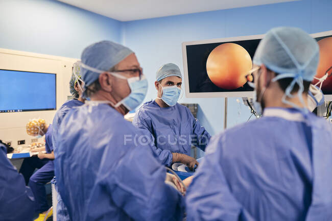 Chirurgiens portant un masque facial discutant pendant l'opération en salle d'opération — Photo de stock