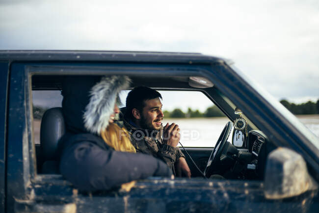 Jeune homme utilisant la radio CB tout en voyageant avec une amie en voiture en hiver — Photo de stock