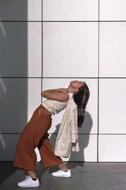 Junge Frau beugt sich bei sonnigem Tag rückwärts an Mauer vorbei — Stockfoto