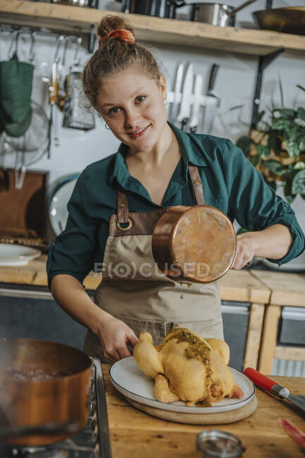 Female chef preparing chicken food while standing in kitchen — Stock Photo