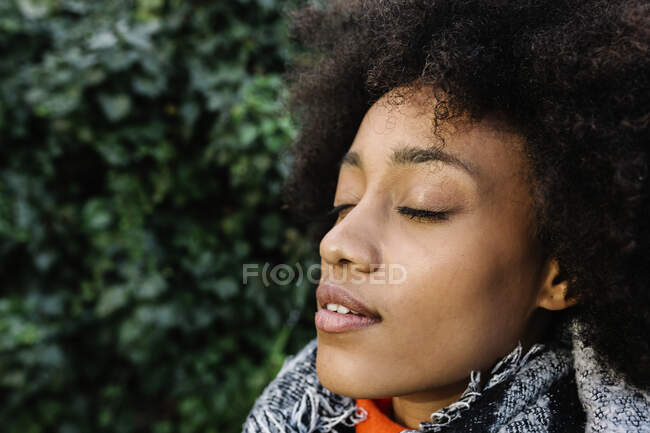Afro mujer joven con los ojos cerrados a la luz del sol - foto de stock