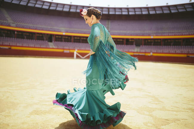 Молода жінка, одягнена в синю сукню фламенко, танцює кільцем. — стокове фото