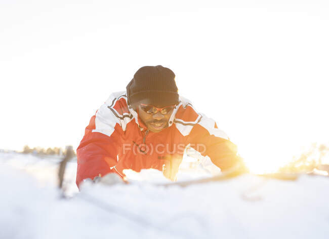 Male athlete looking down while lying on snow during sunset — Stock Photo
