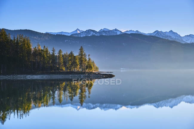 Montañas nevadas reflejadas en el tranquilo lago Walchensee, Baviera, Alemania - foto de stock