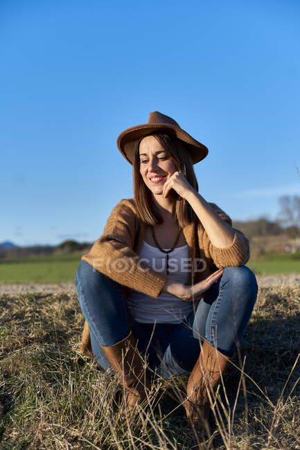Woman with hand on chin looking down while sitting on land against blue sky — Stock Photo
