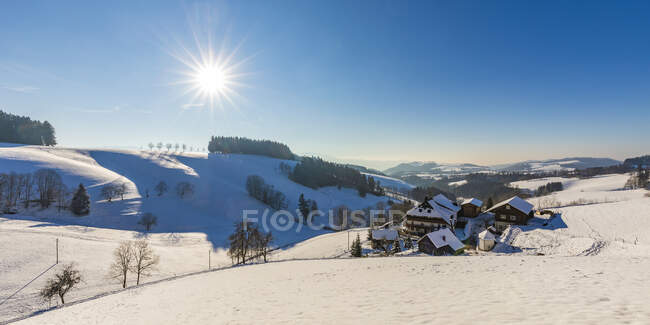 Germany, Baden-Wurttemberg, Sankt Margen, Sun shining over houses of town in middle of Black Forest in winter — Stock Photo