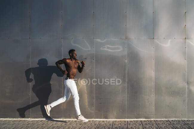 Un hombre sin camisa corriendo por el sendero - foto de stock