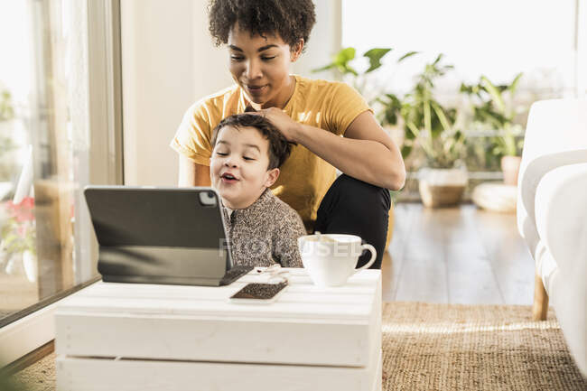 Мать и сын с помощью цифрового планшета, сидя дома — стоковое фото