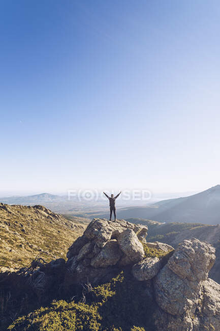 Male hiker with arms outstretched standing on mountain against clear sky — Stock Photo
