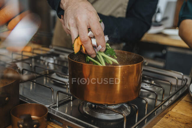 Chef mettere le verdure in pentola di rame mentre facendo brodo zuppa in cucina — Foto stock