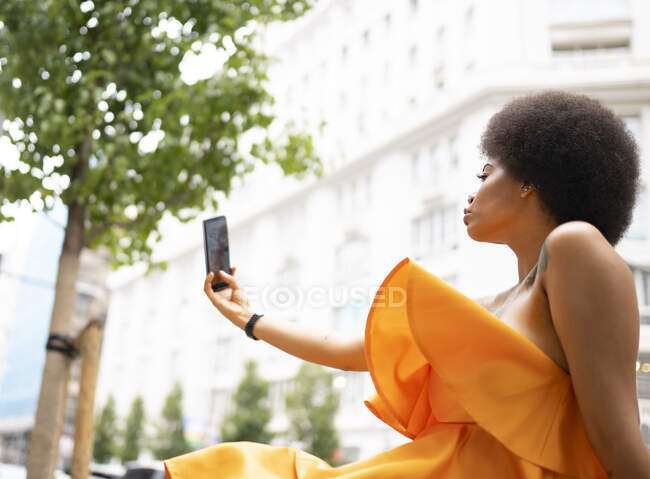 Jovem mulher tomando selfie através de telefone inteligente na cidade — Fotografia de Stock