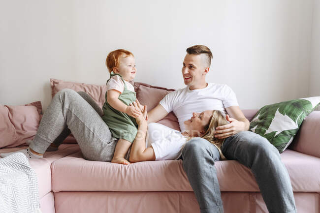Família feliz com bebê filha relaxando no sofá — Fotografia de Stock