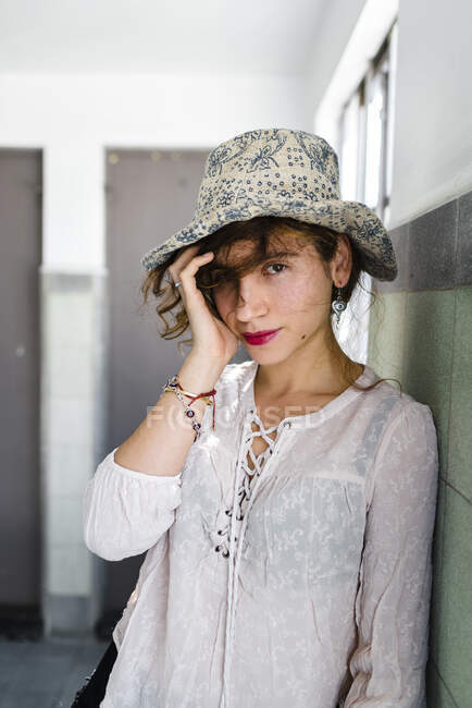 Primo piano di bella donna che indossa cappello in piedi vicino al muro — Foto stock