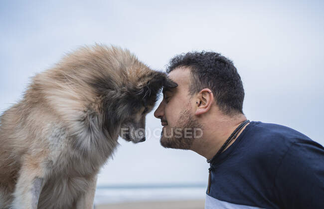 Mann prallt mit Hund am Strand frontal gegen Himmel — Stockfoto