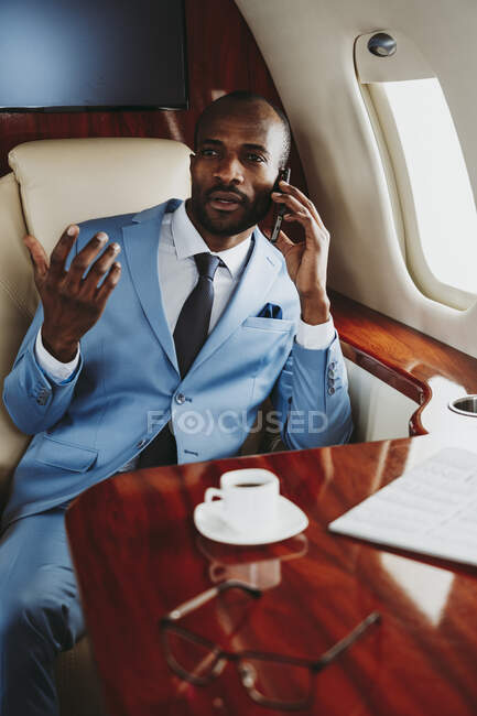 Елегантний бізнесмен розмовляє по смартфону під час подорожі в літаку — стокове фото