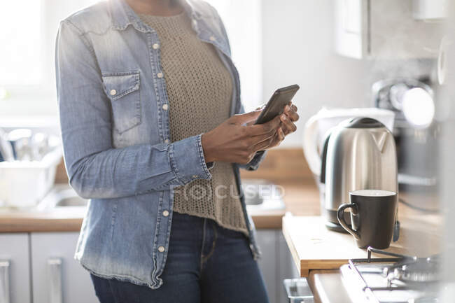 Frau benutzt Smartphone in Küche — Stockfoto