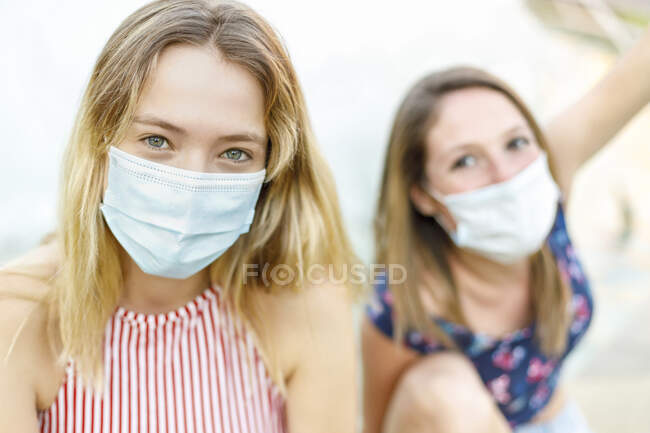 Le amiche che indossano maschere protettive all'aperto — Foto stock