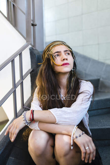 Задумчивая хиппи молодая женщина с длинными волосами сидит на ступеньках — стоковое фото