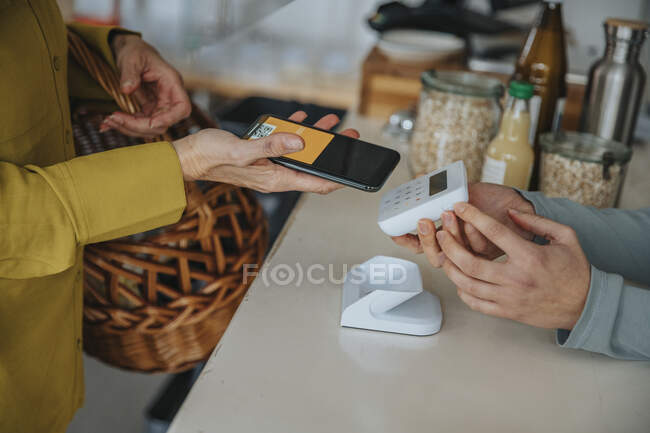 Verkäuferin hält Barcode-Scanner für Kundin, während sie kontaktloses Bezahlen im Laden macht — Stockfoto
