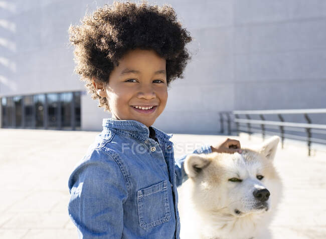 Sorridente ragazzo giocare con cane mentre in piedi all'aperto — Foto stock