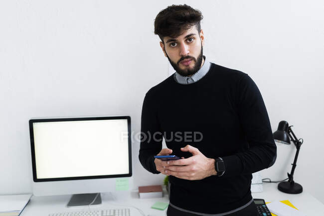 Портрет бизнесмена, держащего смартфон в офисе — стоковое фото