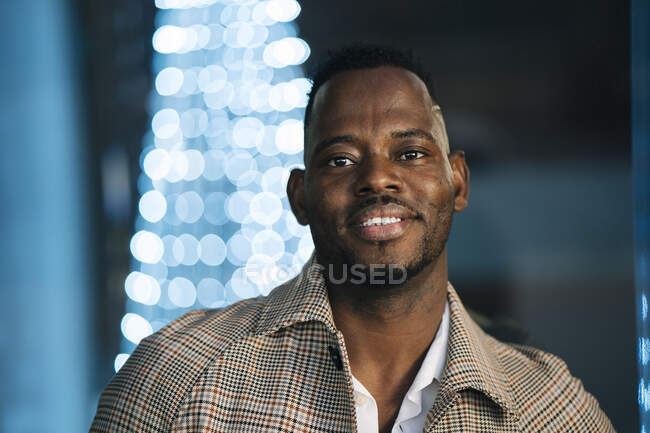 Hombre africano sonriente en abrigo por la noche - foto de stock