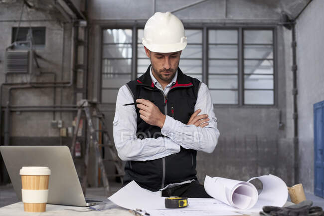 Homme ingénieur penser tout en analysant le plan sur la table dans la construction — Photo de stock