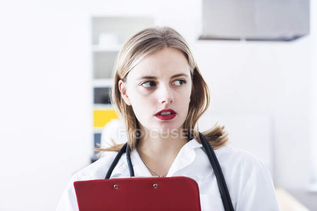 Médecin féminin avec presse-papiers regardant loin en laboratoire — Photo de stock