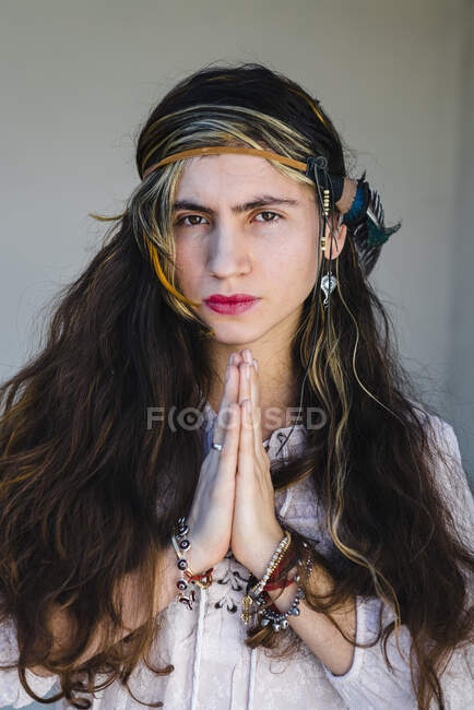 Primer plano de la mujer hippie de pie en la oración posan contra la pared - foto de stock