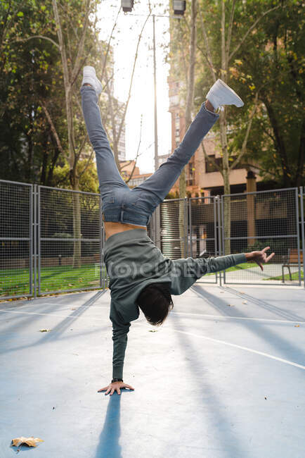 Uomo acrobatico con segnale di clacson che fa stand al campo da basket nel campus durante l'autunno — Foto stock