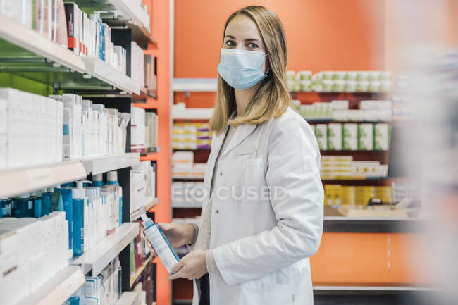 Farmacista donna con maschera protettiva mentre lavora in farmacia — Foto stock