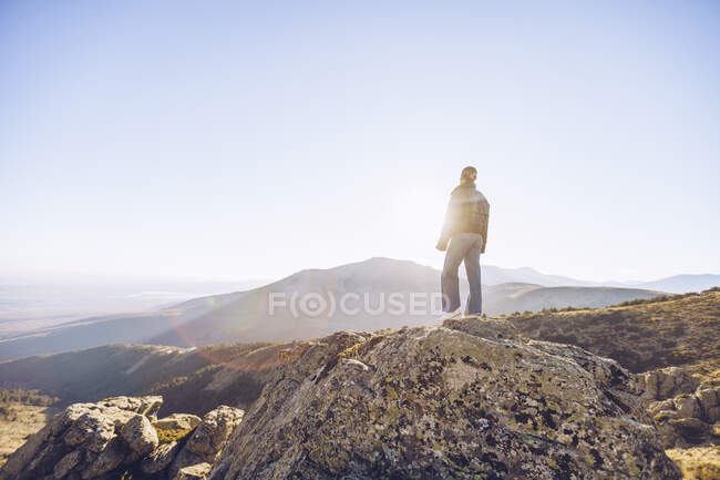 Escursionista donna in piedi sulla cima della montagna contro il cielo limpido durante la giornata di sole — Foto stock