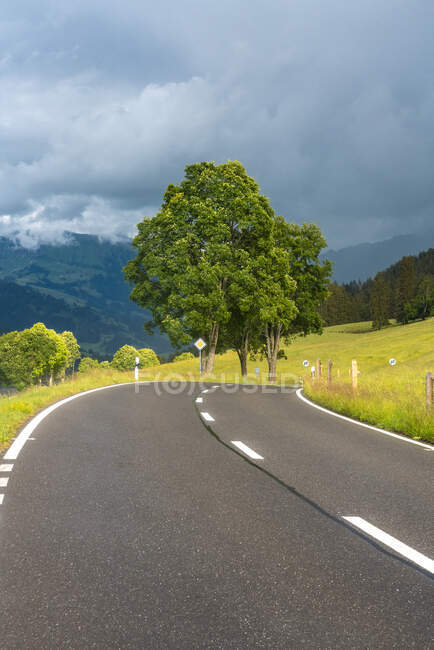 Уменьшающаяся перспектива горной дороги против облачного неба, Берн, Швейцария — стоковое фото