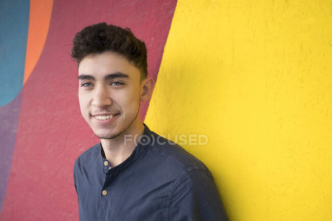 Sourire jeune homme contre le mur multicolore — Photo de stock