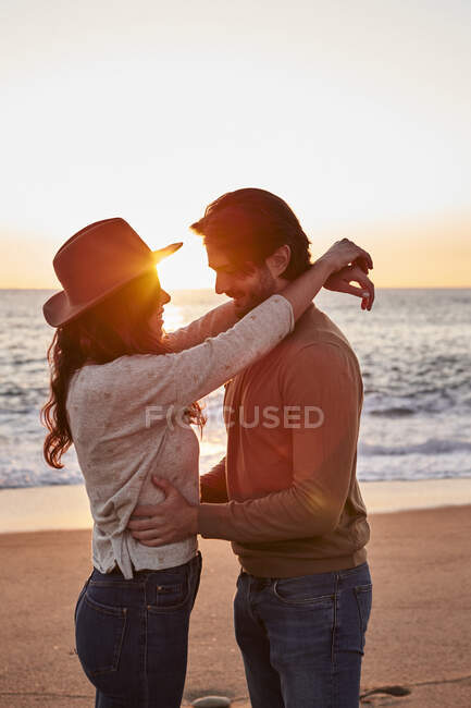 Casal jovem dançando em pé na praia durante o nascer do sol — Fotografia de Stock