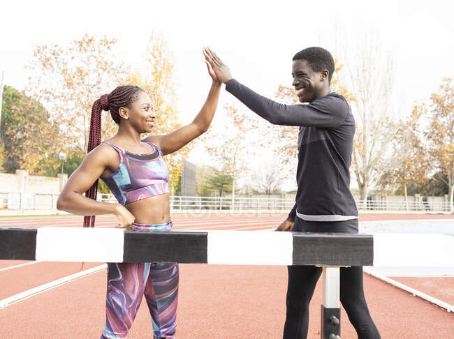 Sportler geben High-Five im Stehen am Balken auf Laufstrecke — Stockfoto