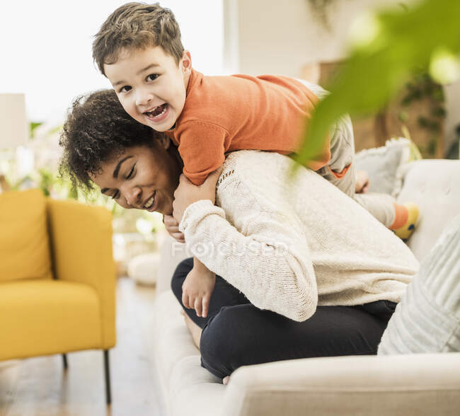 Mère et fils joyeux jouant tout en étant assis sur le canapé à la maison — Photo de stock