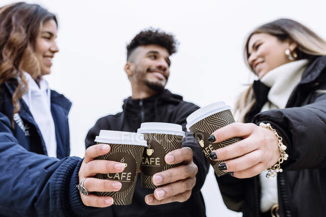 Smiling friend toasting coffee cups while looking at each other — Stock Photo
