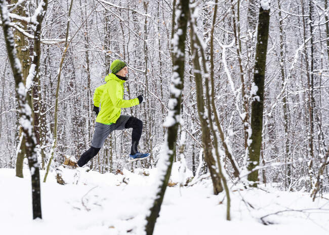 Sportler läuft im Winter auf Schnee im Wald — Stockfoto