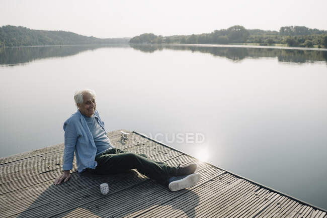 Sorrindo homem olhando para longe enquanto relaxa no cais — Fotografia de Stock