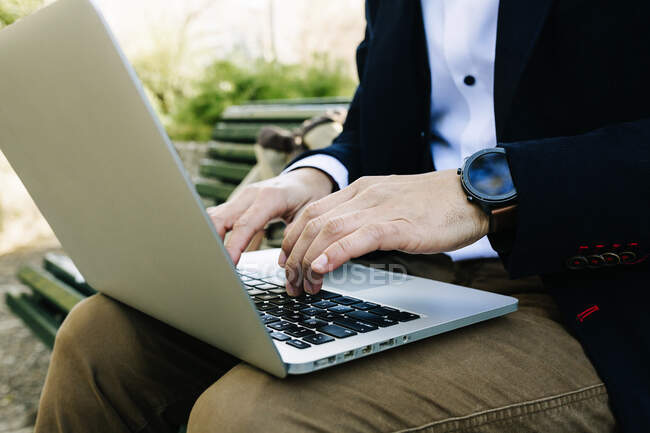 Бізнесмен за допомогою ноутбука сидячи на лавці. — стокове фото