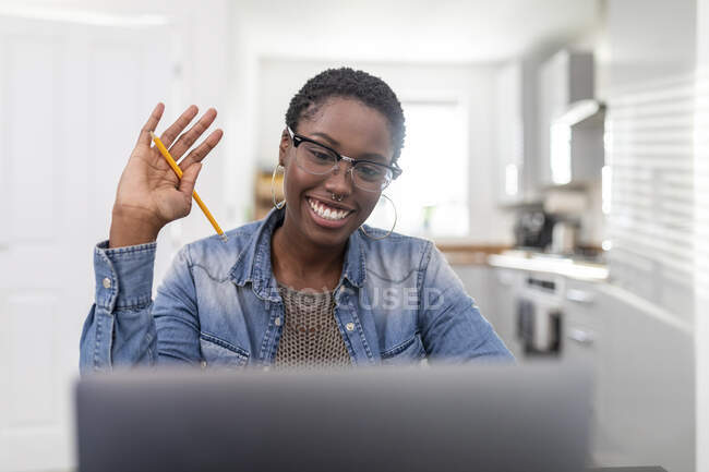 Mujer trabajando teniendo videollamada vía laptop en casa - foto de stock