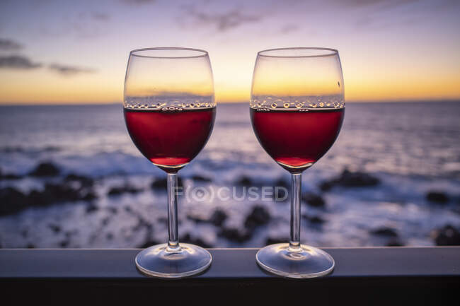 Дві склянки червоного вина з морем на заході сонця на задньому плані — стокове фото