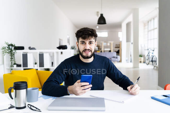 Портрет молодого бизнесмена, пишущего за столом в творческом кабинете — стоковое фото