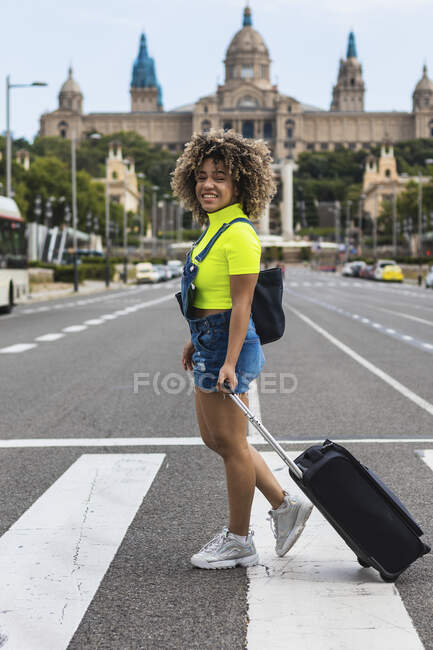 Усмішка самки колеса багаж під час ходьби по вулицях міста. — стокове фото