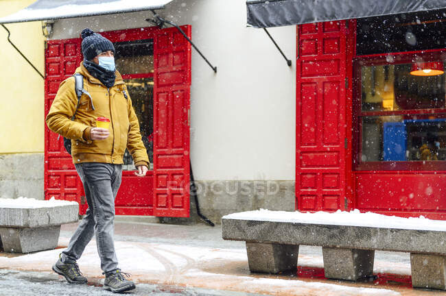 Hombre con mascarilla protectora caminando por la carretera durante COVID-19 - foto de stock