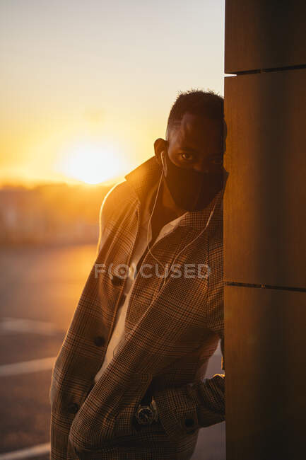 Man listening to music while leaning on pillar during sunset — Stock Photo