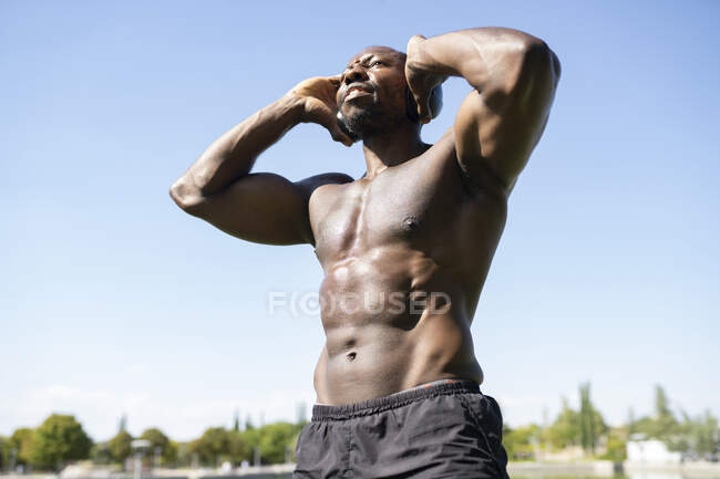 Atleta di sesso maschile ascoltare musica contro il cielo limpido nella giornata di sole — Foto stock